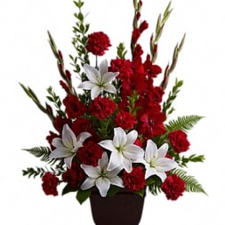 Red carnations and white lilies in a dark vase