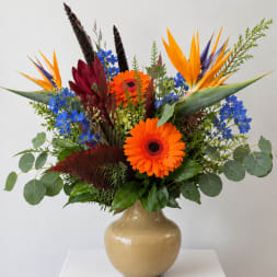 Bright mixed bouquet in a beige vase with orange and blue flowers