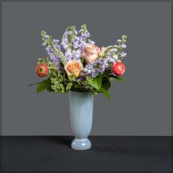 Lavender flowers and peach roses in a tall white vase