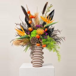 Tropical arrangement with orange bird-of-paradise in a striped vase