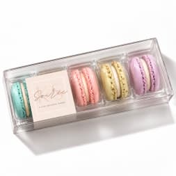 Box of pastel macarons in a clear plastic tray
