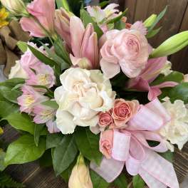 Pink and white bouquet with roses, lilies, and a ribbon bow