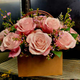Pink roses arranged in a brown box with small purple filler flowers