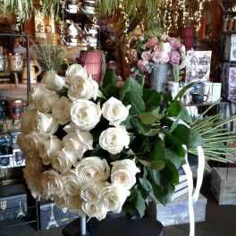 Large bouquet of white roses with green leaves and white ribbon