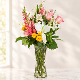 Mixed bouquet of pink and white flowers in a clear glass vase