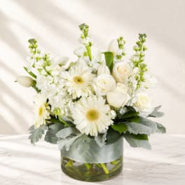 White flowers arranged in a glass vase with silver ribbon