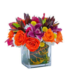 Bright bouquet of orange roses and purple flowers in a glass vase