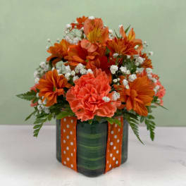 Orange bouquet in a green vase with a polka-dot ribbon