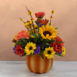 Colorful mixed flower arrangement in an orange pumpkin-shaped vase