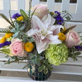 Mixed bouquet with pink roses, white lilies, and yellow blooms in a mosaic vase