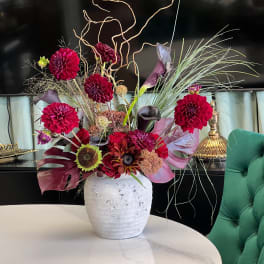 Tall floral arrangement with magenta blooms in a white vase