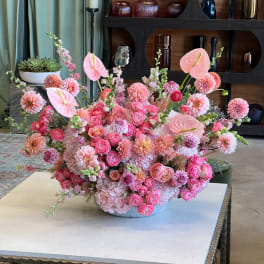 Large pink floral arrangement in a low white bowl with anthuriums and dahlias