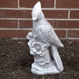 White bird statue holding a flower against a brick wall