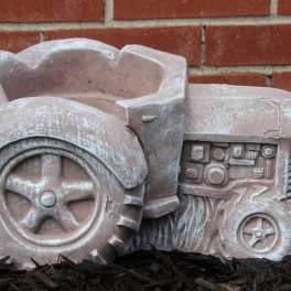 Decorative tractor-shaped planter in a garden bed