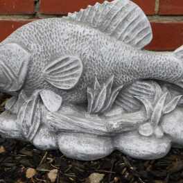 Gray fish garden statue on a brick and mulch background