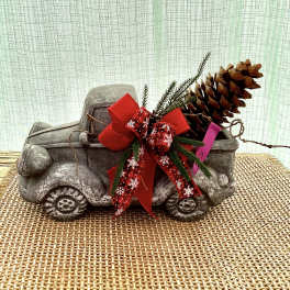 Decorative stone truck with a red holiday bow and pinecone accent