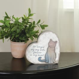 Potted green plant beside a heart-shaped memorial plaque with a cat illustration