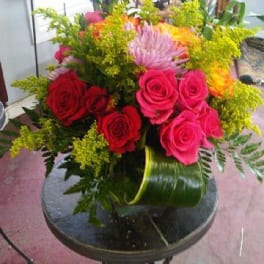 Bouquet of pink and red roses with yellow filler in a green vase