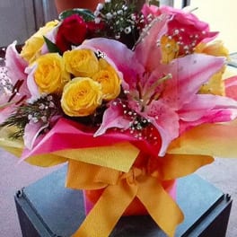Bouquet of pink lilies and yellow roses with a large ribbon
