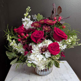 Bouquet of red roses, white hydrangeas, and burgundy daisies in a silver vase