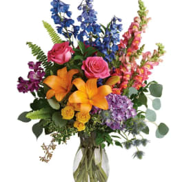 Mixed bouquet with roses, lilies, delphinium, and snapdragons in a glass vase