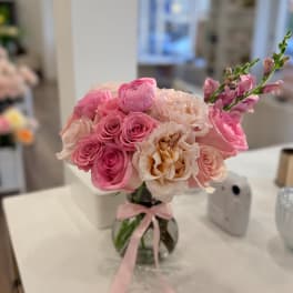 Pink and blush roses arranged in a glass vase with a ribbon