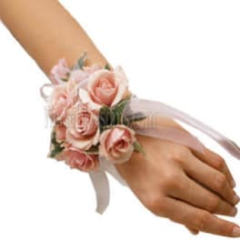 Wrist corsage of light pink roses with white ribbon on a person's hand