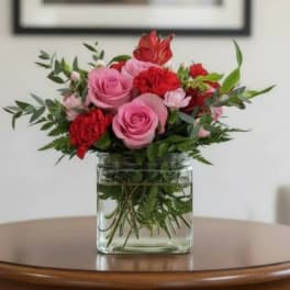 Pink and red roses arranged in a clear glass vase