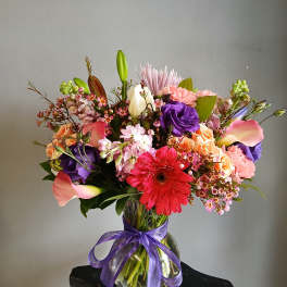 Colorful mixed bouquet in a glass vase tied with a purple ribbon
