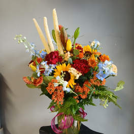 Mixed bouquet in a glass vase with sunflowers, red carnations, and blue flowers