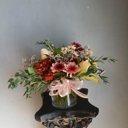 Mixed bouquet in a glass vase with a pink ribbon