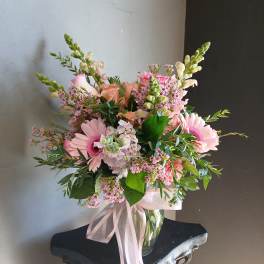 Pink mixed bouquet in a clear glass vase with a pale ribbon