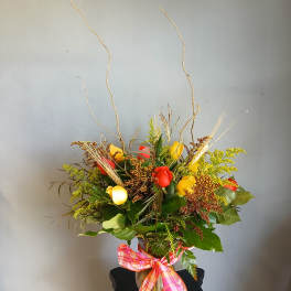 Mixed bouquet of red and yellow roses in a vase with a plaid ribbon