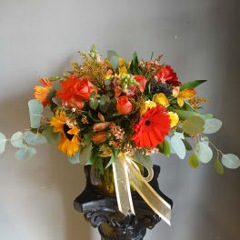 Colorful mixed bouquet in a glass vase with a gold ribbon