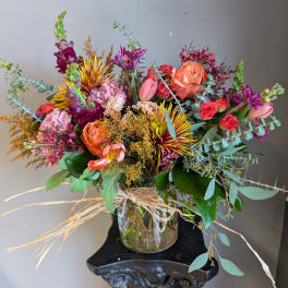 Mixed bouquet of roses, tulips, and purple blooms in a glass vase