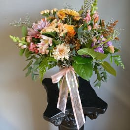 Mixed bouquet in a glass vase with a pink ribbon