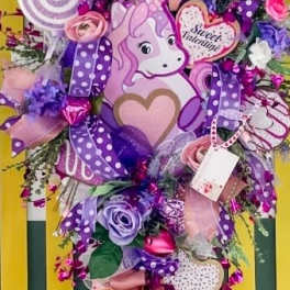 Unicorn-themed bouquet with pink and purple flowers, ribbons, and candy decorations