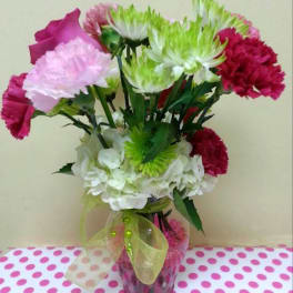 Pink, white, and green carnations in a glass vase with a ribbon