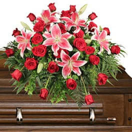 Red roses and pink lilies arranged on a wooden casket