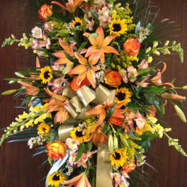 Large standing floral spray with orange lilies, sunflowers, and roses
