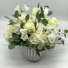 White roses and hydrangeas in a ribbed silver vase