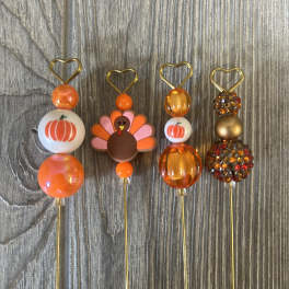 Four decorative pumpkin and turkey picks on thin metal stems