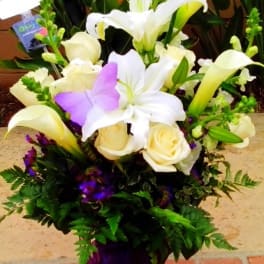Bouquet of white lilies, cream roses, and purple butterflies in a purple wrap