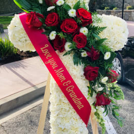 Standing floral cross with red roses and white flowers on an easel