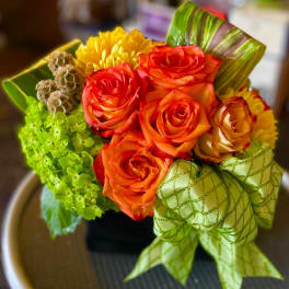 Bouquet of orange roses and yellow mums with a green ribbon bow