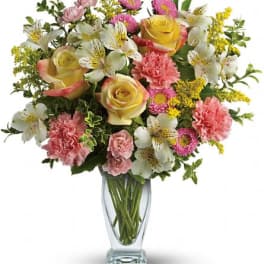 Mixed bouquet of roses, carnations, and white alstroemeria in a glass vase