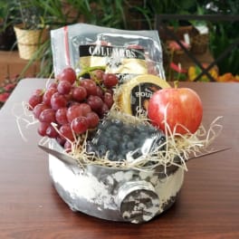 Fruit gift basket with grapes, an apple, and packaged snacks in a metal container