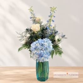 Blue hydrangeas and white roses in a teal glass vase