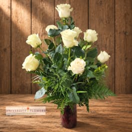 Cream roses arranged in a dark glass vase with greenery