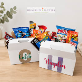Two personalized snack gift boxes filled with candy and chips on a table
